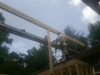Carpenter setting a ridge beam over a new addition frame — Ice Dam Removal by Roofing Brothers in Castalia