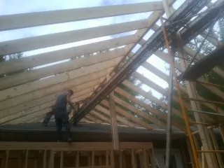 Rafters going up over a new addition with a worker on the wall in Castalia