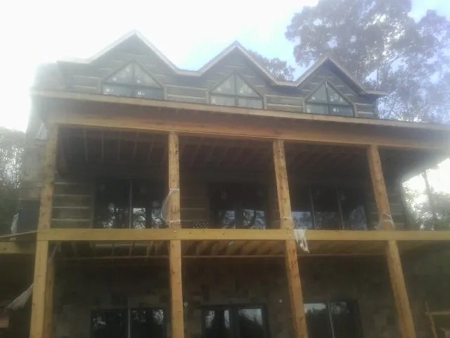 Dormers and porch framing on a large log home under construction — Roof Coating work by our crew in Castalia