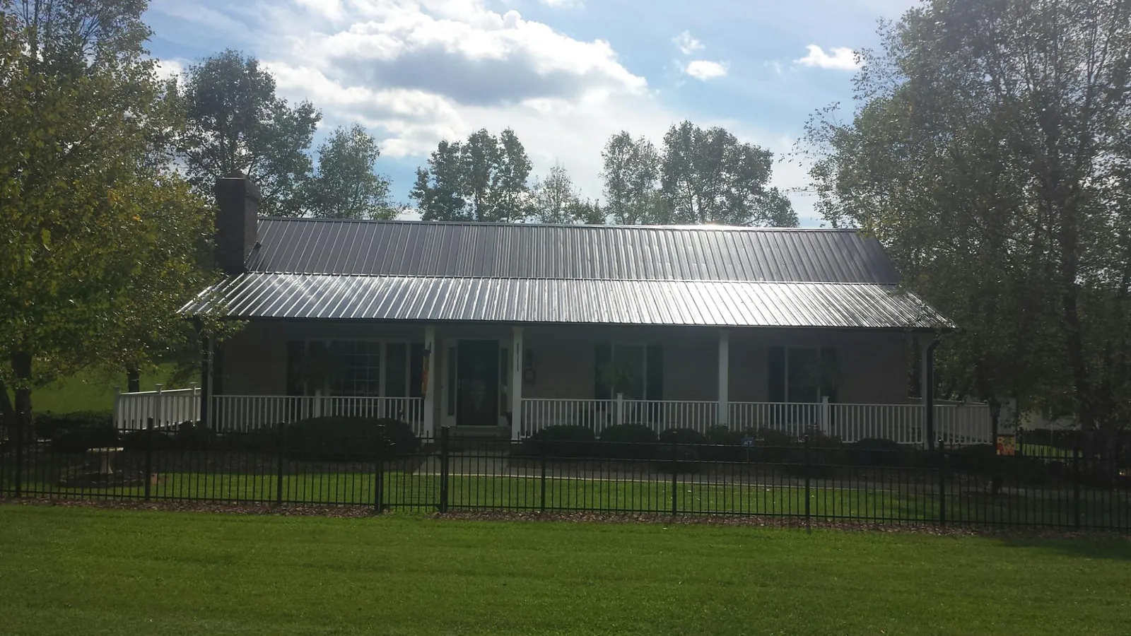 Gray metal roof on a brick ranch with a full width front porch — Gutter Guard Installation work by our crew in Castalia