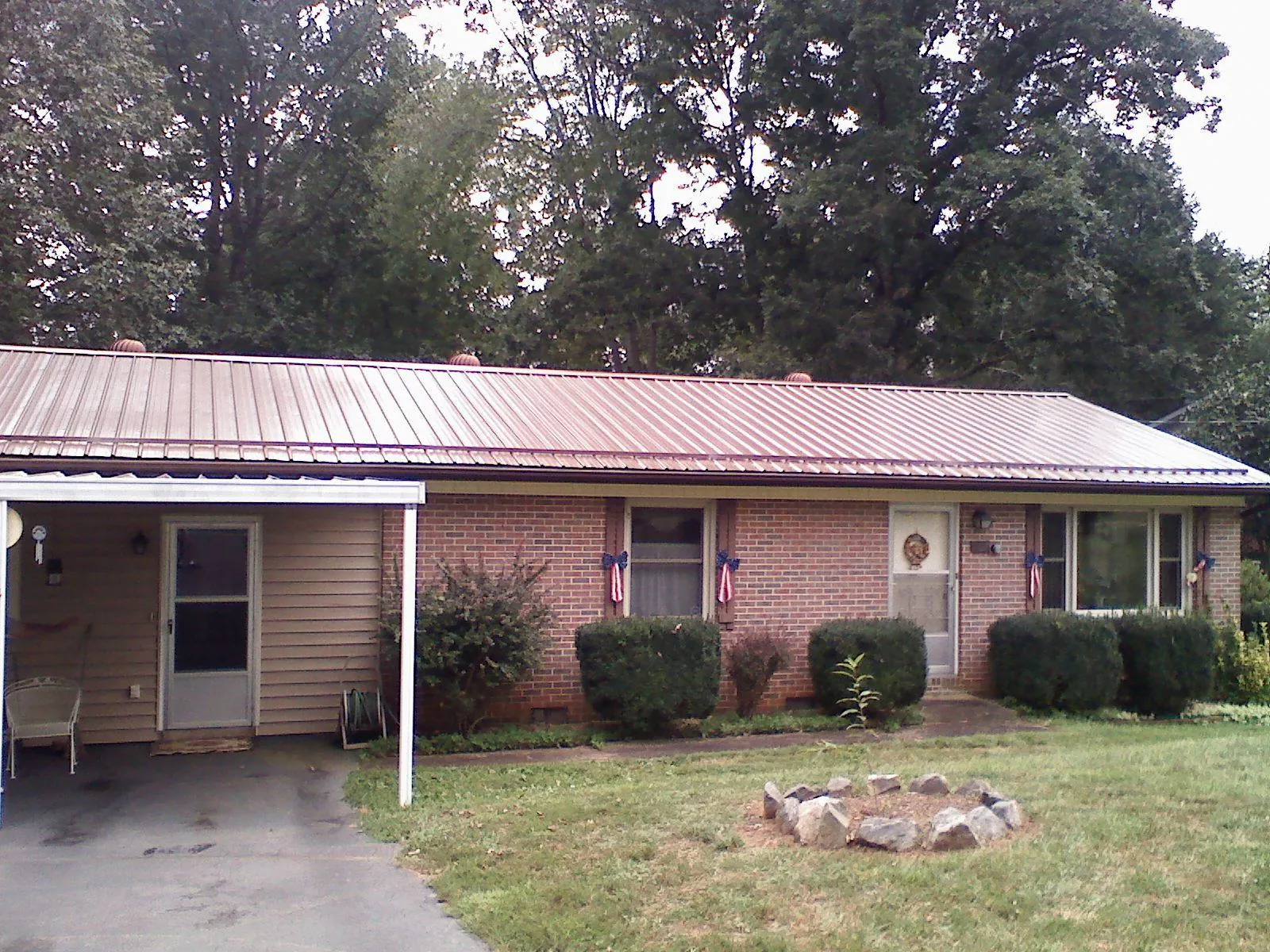 Bronze metal roof and carport on a brick ranch home — Roof Repair work by our crew in Castalia