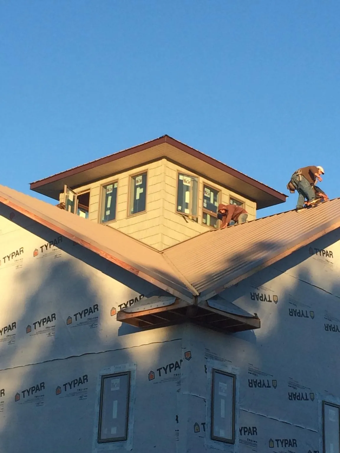 Roofers working around a rooftop cupola on a new metal roof at sunset — Roof Waterproofing in Castalia by Roofing Brothers